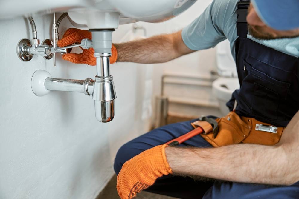 Handyman repairing leaky plumbing